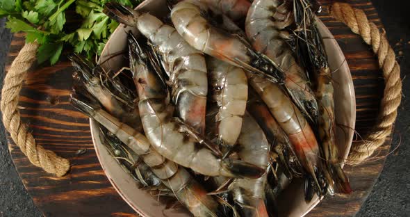 Raw Shrimps on a Wooden Tray with Greens Rotate. 