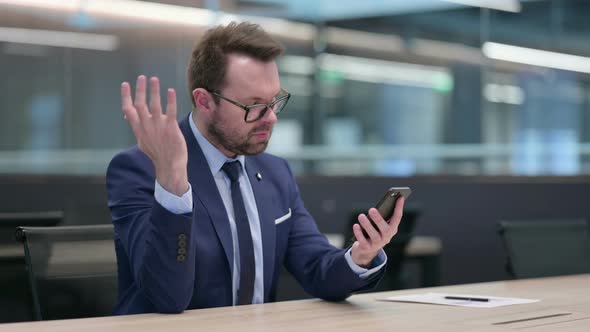 Middle Aged Businessman Reacting to Loss on Smartphone