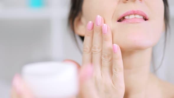 Extreme Closeup Female Hand Applying White Moisturizing Cream to Chin