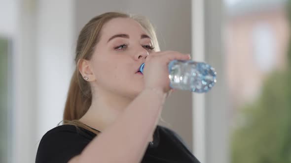 Closeup Face of Exhausted Plump Sportswoman Drinking Refreshing Water After Training Indoors