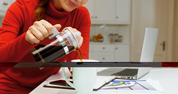 Woman pouring coffee into cup in kitchen 4k