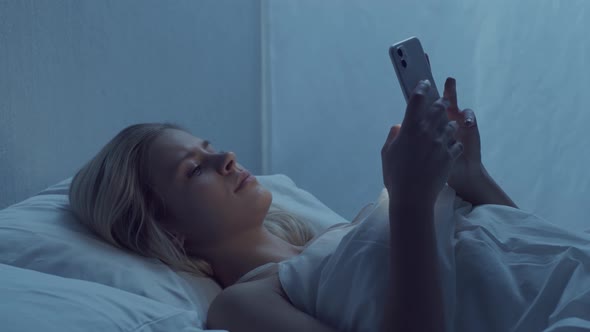 Young woman lying in the bed at night. Beautiful sleeping girl. Twilight in the bedroom.