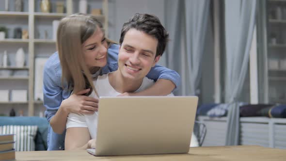 Casual Happy Young Couple Using Laptop at Home