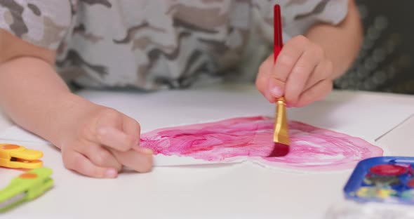 Close Up of a Little Boy's Hands Who is Filling a Red Heart with Red