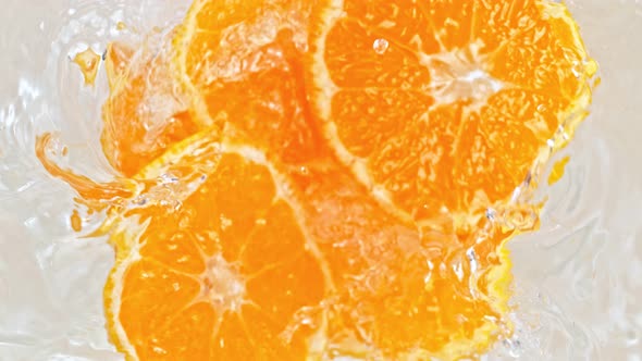 Super Slow Motion Shot of Orange Slices Falling Into Water Whirl at 1000 Fps alt