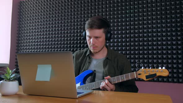 Male Learning Play Guitar at Home Using Online Lessons