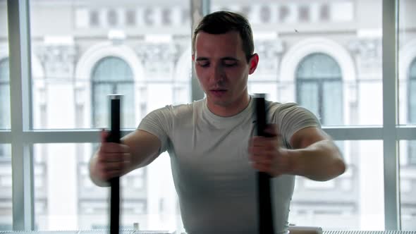 Modern Gym - a Young Guy Doing Arm Exercise on the Training Apparatus
