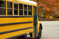 Yellow school bus stands in parking lot against the background of autumn park. - PhotoDune Item for Sale
