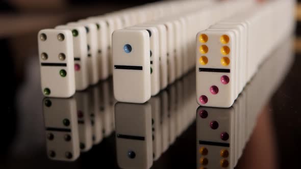 Three Rows of Dominoes are Slowly Falling on a Black Mirror Background