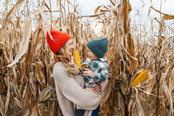Mother and son exploring corn harvest in background of an agricultural field area.