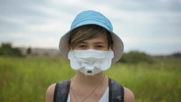 Boy in a Protective Mask Stands Outdoors and Looks at the Camera, Pandemic Concept