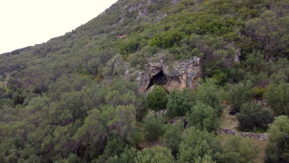 Amazing long aerial view flight fly backwards drone footage of a big cave in a mountain in the wild