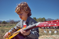 Little boy playing acoustic guitar on sunny day in countryside - PhotoDune Item for Sale
