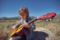 Cute kid playing guitar on hay bale in field - PhotoDune Item for Sale