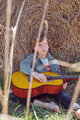 Thoughtful boy with acoustic guitar near hay bale - PhotoDune Item for Sale