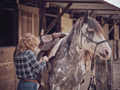 Unrecognizable woman putting on saddle on horse - PhotoDune Item for Sale