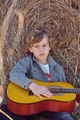 Sad boy with guitar sitting near hay bale - PhotoDune Item for Sale