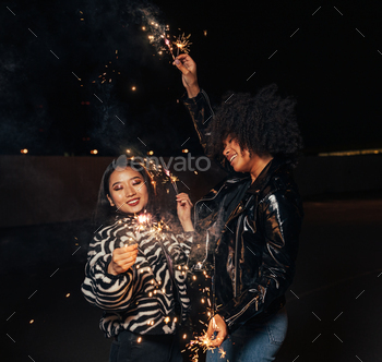 Two happy girls with sparklers enjoying a party at night