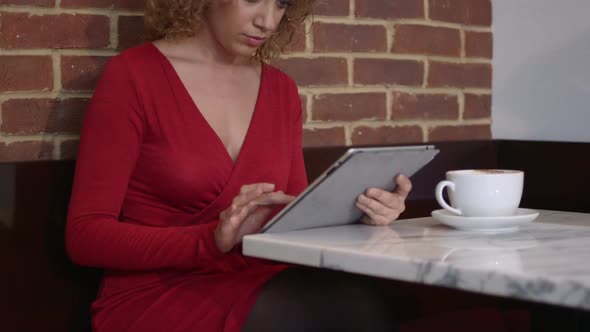 MS Young woman sitting in caf and using digital tablet / London, Greater London, United Kingdom.