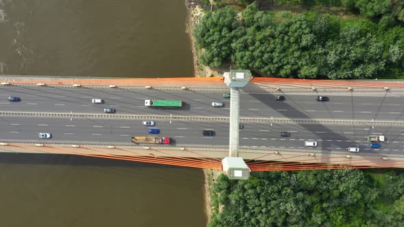 City caring at highway bridge on background smooth river surface drone view