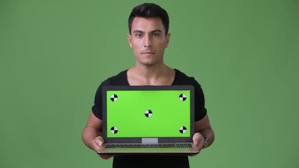 Young Handsome Hispanic Man Against Green Background