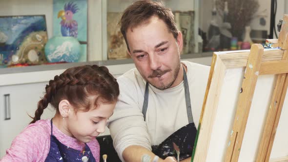 Happy Little Girl Painting a Picture with Her Father