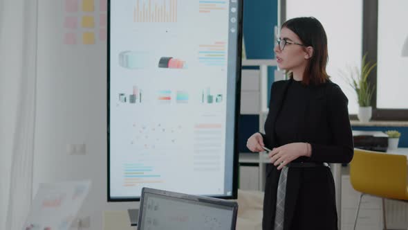 Businesswoman Pointing at Television with Data Charts