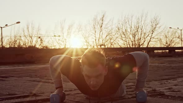 Young and fit man having evening workout outdoor. Urban sunset background.