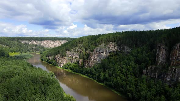 Fly over river near a high cliff of eroded sedimentary rocks of Ural Mountains