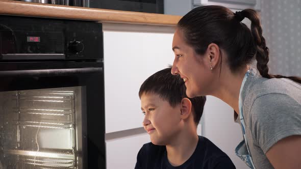 Woman and Boy Look Into the Oven While Waiting for a Dish