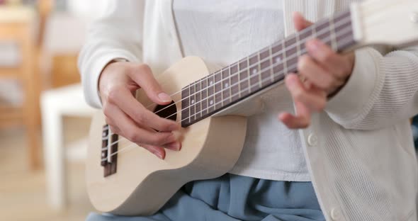 Woman play ukulele at home