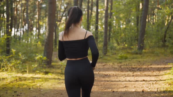 Girl in Sportswear Runs Along the Path in Forest