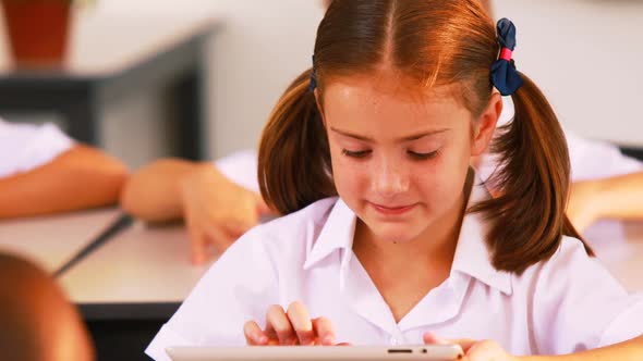 Schoolgirl using digital tablet in classroom