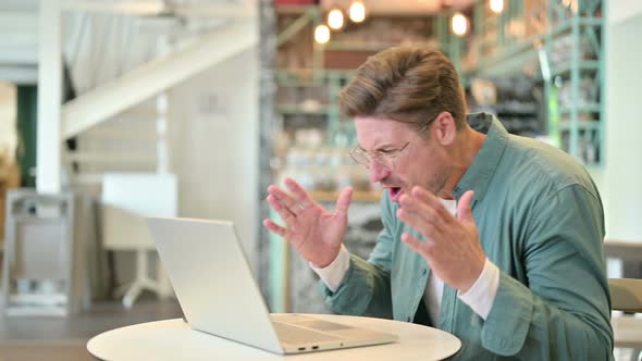 Loss, Middle Aged Man Reacting To Failure on Laptop in Cafe 