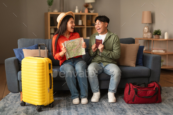 Excited Korean Tourists Couple Holding Travel Map And Tickets Indoors