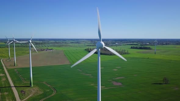 Aerial view of wind turbines generating renewable energy in the wind farm, sunny spring day, low fly