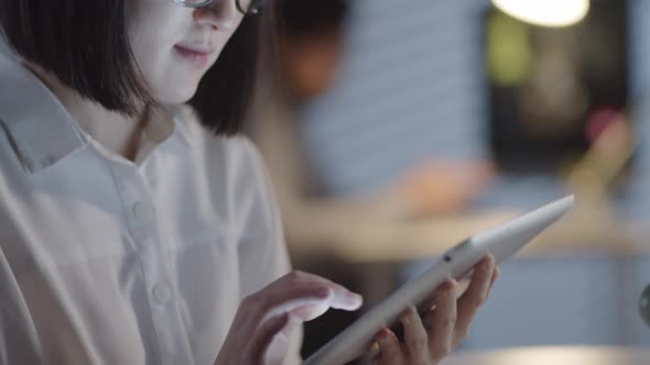 Asian Businesswoman Using Tablet in Dark Office