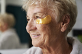 Senior caucasian woman applying medical eye patch in the bathroom - PhotoDune Item for Sale