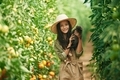 Smiling, holding kitten. Little girl is in the garden with tomatoes - PhotoDune Item for Sale