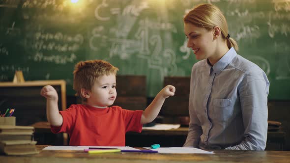 Preschool Female Teacher Teaching Kid in Classroom. Kindergarten Preschool Concept. Smiling