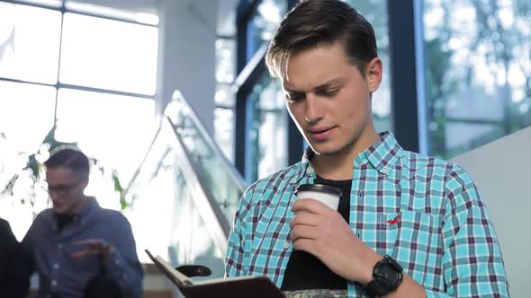 Man Reading Notes And Drinking Coffee At Campus Building