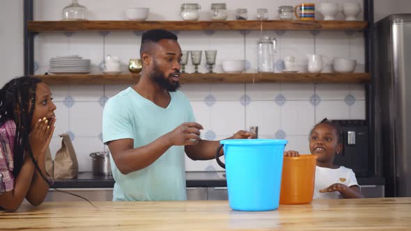 African Family Holding Bucket While Water Leaking From Ceiling in Kitchen