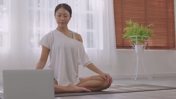 Morning yoga with an Asian woman, sitting in Easy position,