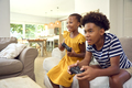 Brother And Sister Sitting On Sofa At Home Playing Video Game Together - PhotoDune Item for Sale