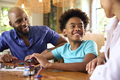 Family Around Table At Home Using Laptop With Parents Helping Son With Science Homework - PhotoDune Item for Sale