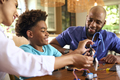 Family Around Table At Home Using Laptop With Parents Helping Son With Science Homework - PhotoDune Item for Sale