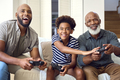Multi-Generation Male Family Sitting On Sofa At Home Playing Video Game Together - PhotoDune Item for Sale