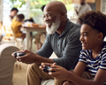 Grandfather And Grandson Sitting On Sofa At Home Playing Video Game Together - PhotoDune Item for Sale