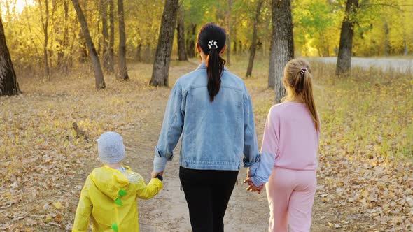 Mother and Two Children Walking in the Park and Enjoying the Beautiful Autumn Nature