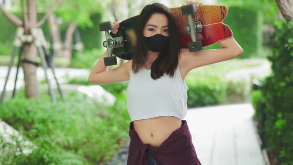 Attractive Asian woman smiling  play skateboard outdoor garden.